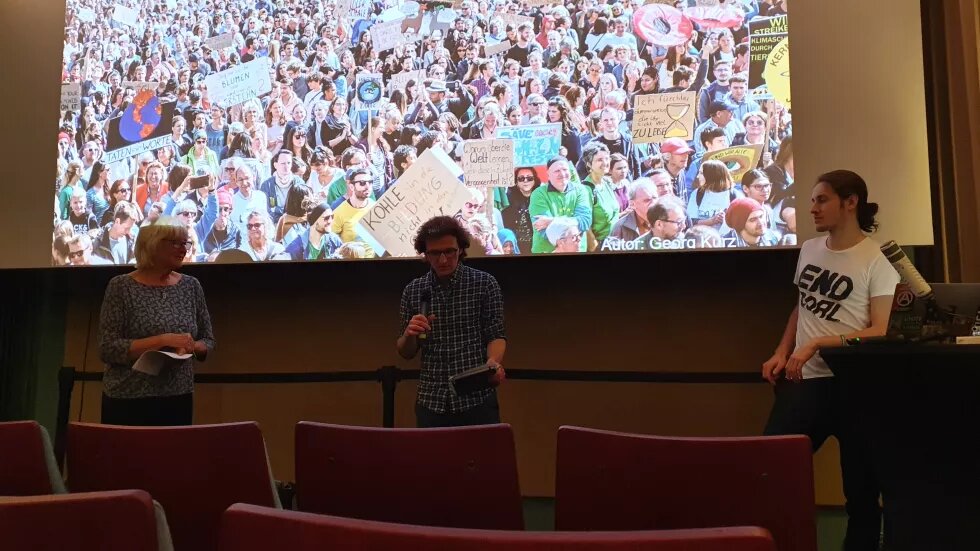 Sara Parkin, Stephen Milder und Yannick Kiefl diskutieren vor dem Leinwand