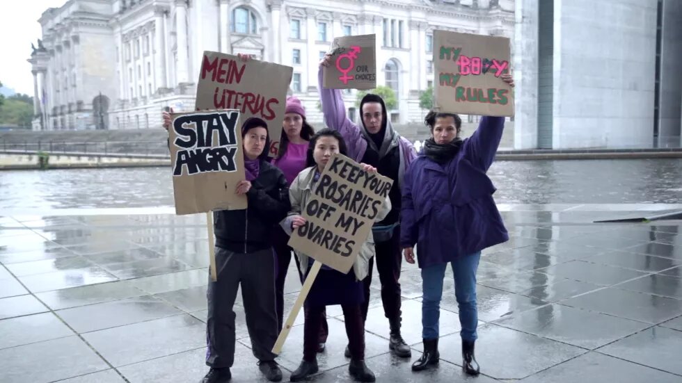 Shot aus dem Film, Frauen halten Protestschildern